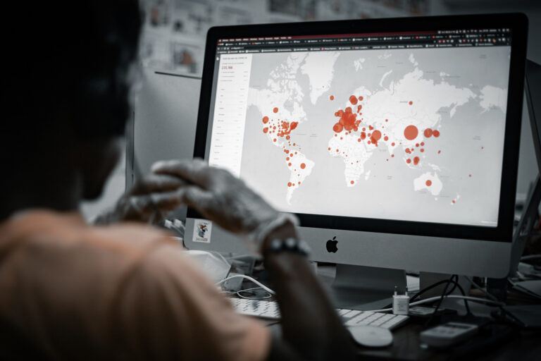 Unidentified person looking at a computer screen showing a world map of outbreak areas