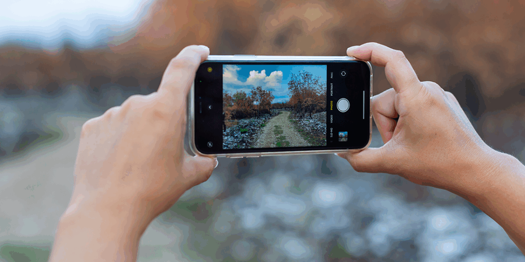 first-person view of phone camera, held by two hands, taking photo of scenery