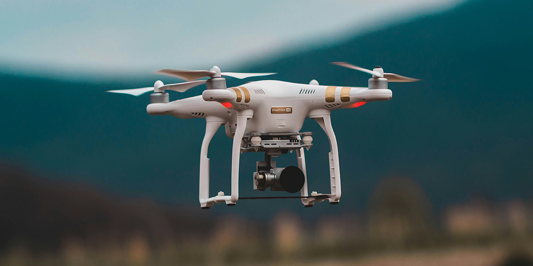 flying drone with a camera attached on the bottom, blurred background