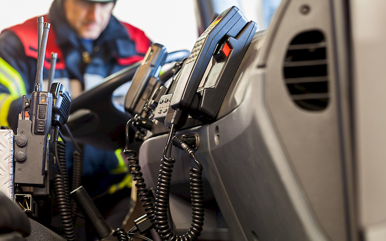 portable radios mounted inside a vehicle with a public safety person standing outside the vehicle