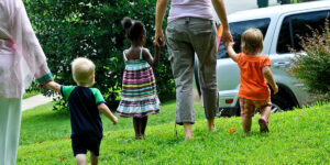 two adults walking hand in hand with three young children