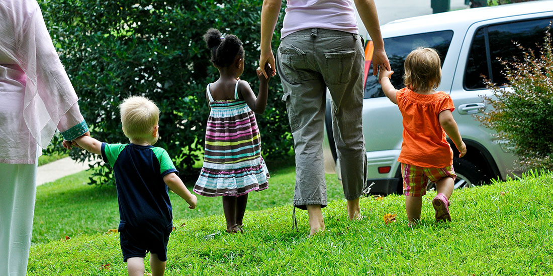 two adults walking hand in hand with three young children