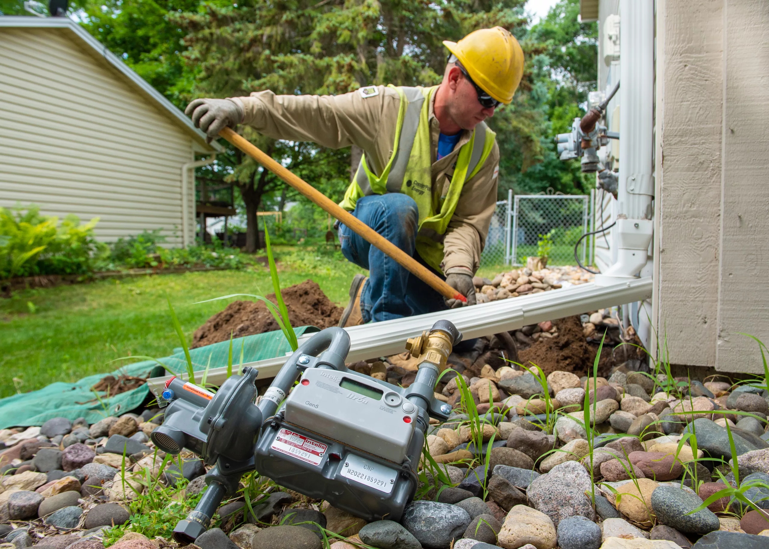 Man kneeling next to a building while working on a natural gas line