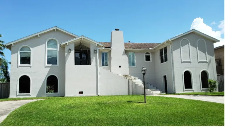 Two-level stucco house with water damage on stairs