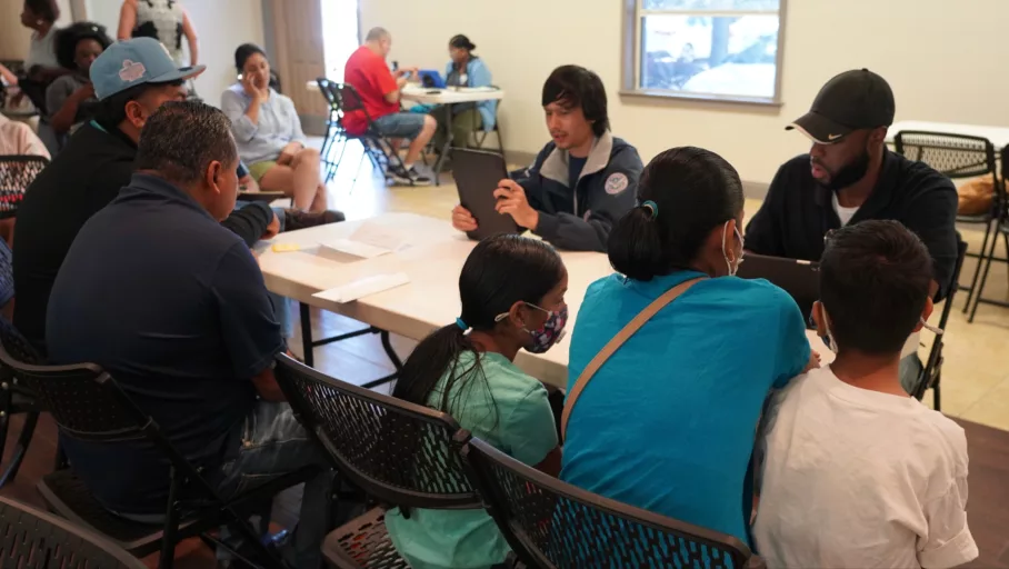 Two FEMA personnel sitting at a desk with two men, a woman, and two children