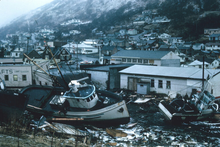 fishing boats on land next to buildings that have been heavily damage due to a tsunami