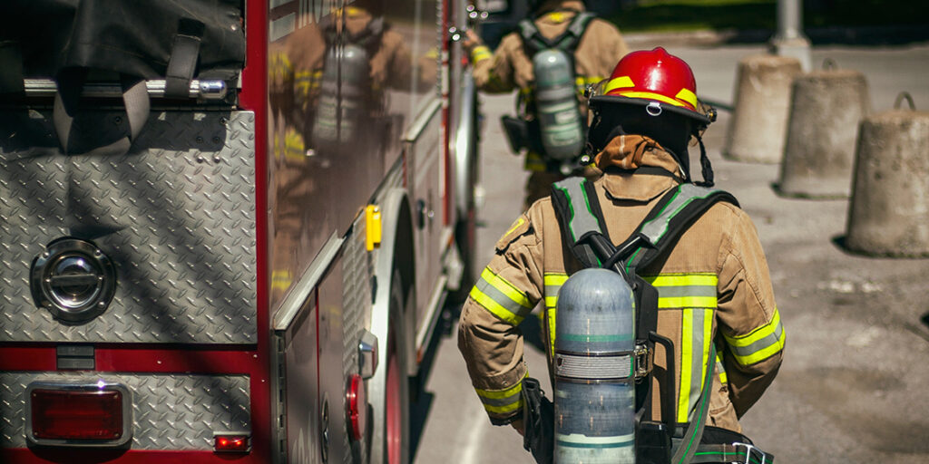 Firefighter with protection clothes running toward front of truck away from viewer