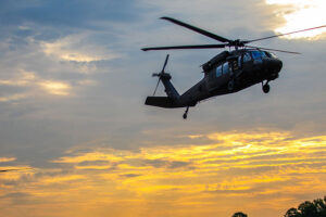 2 helicopters flying low in sunset sky