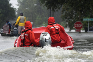 Coast Guardsmen in an inflatable motor boat motoring down a flooded street