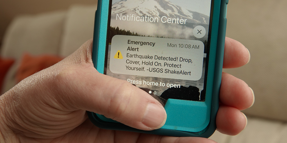Close up of a hand holding a phone with an emergency earthquake