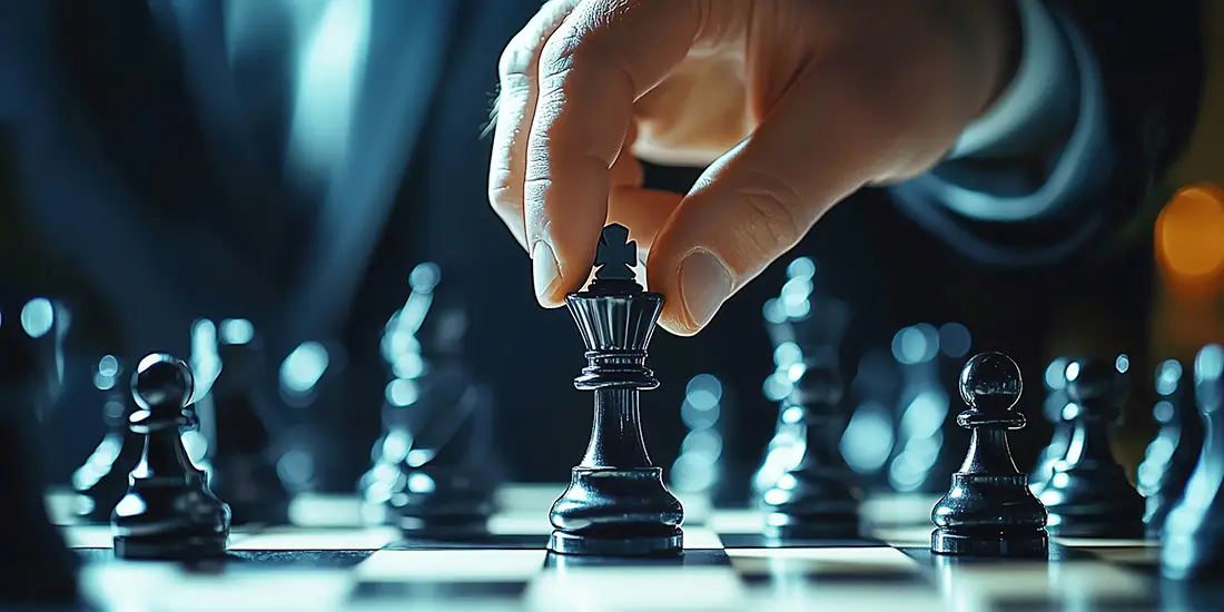 A focused player moves a black king in a tense chess match under dim lighting, showcasing concentration and skill in a competitive environment.