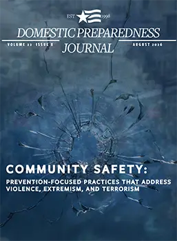 Cover of Domestic Preparedness Journal, Volume 22, Issue 8 (August 2026). The cover features a blue-toned image of shattered glass with a large circular impact point and radiating cracks. Overlaid white text reads: “Community Safety: Prevention-Focused Practices That Address Violence, Extremism, and Terrorism.” The journal title appears at the top with publication details and a stylized star logo.