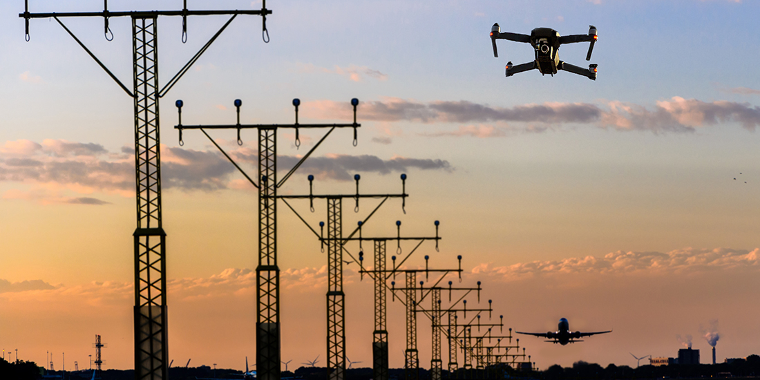 Unmanned drone flying near runway at airport while commercial airplane takes off leading to possible collision.